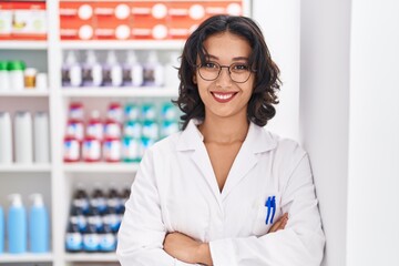 Canvas Print - Young beautiful hispanic woman pharmacist smiling confident standing with arms crossed gesture at pharmacy