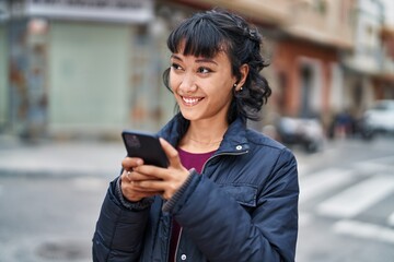 Wall Mural - Young beautiful hispanic woman smiling confident using smartphone at street