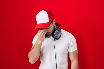 Canvas Print - Hispanic man with beard wearing gamer hat and headphones tired rubbing nose and eyes feeling fatigue and headache. stress and frustration concept.