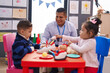 © Krakenimages.com - Hispanic man with boy and girl playing supermarket game sitting on table at kindergarten