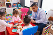© Krakenimages.com - Hispanic man and girls playing supermarket game sitting on table at kindergarten