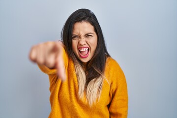 Wall Mural - Young hispanic woman standing over isolated background pointing displeased and frustrated to the camera, angry and furious with you