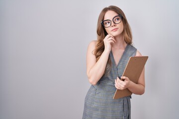 Poster - Caucasian woman wearing glasses and business clothes with hand on chin thinking about question, pensive expression. smiling with thoughtful face. doubt concept.