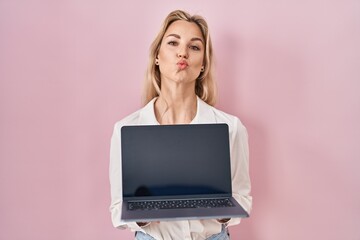 Sticker - Young caucasian woman holding laptop showing screen looking at the camera blowing a kiss being lovely and sexy. love expression.