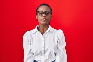 Sticker - African woman with braids standing over red background making fish face with lips, crazy and comical gesture. funny expression.