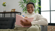 © Krakenimages.com - African american woman writing on notebook sitting on sofa at home