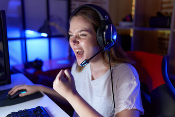 Poster - Young caucasian woman streamer playing video game using computer at gaming room