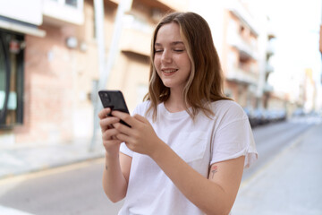 Wall Mural - Young caucasian woman smiling confident using smartphone at street