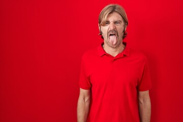 Poster - Caucasian man with mustache standing over red background sticking tongue out happy with funny expression. emotion concept.