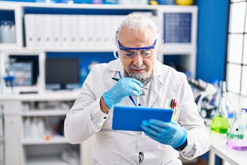 Wall Mural - Middle age grey-haired man scientist using touchpad at laboratory