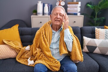 Canvas Print - Middle age grey-haired man suffering for headache sitting on sofa at home