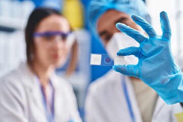 Canvas Print - Man and woman scientists looking sample at street