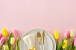 Mother's Day celebration concept. Top view photo of circle plate cutlery knife fork fabric napkin with ring yellow pink tulips on isolated pastel pink background with empty space