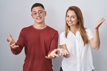 Poster - Mother and son standing together over isolated background smiling cheerful offering hands giving assistance and acceptance.