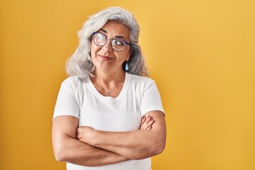 Wall Mural - Middle age woman with grey hair standing over yellow background smiling looking to the side and staring away thinking.