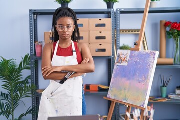 Poster - Young african american with braids at art studio painting on canvas skeptic and nervous, disapproving expression on face with crossed arms. negative person.