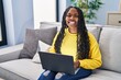 © Krakenimages.com - African american woman using laptop sitting on sofa at home