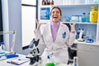 © Krakenimages.com - Young brunette woman working at scientist laboratory celebrating mad and crazy for success with arms raised and closed eyes screaming excited. winner concept