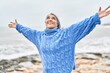 © Krakenimages.com - Middle age grey-haired woman smiling confident standing with arms open at seaside