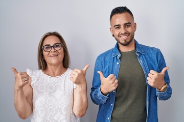 Poster - Hispanic mother and son standing together success sign doing positive gesture with hand, thumbs up smiling and happy. cheerful expression and winner gesture.