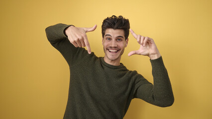 Wall Mural - Young hispanic man smiling confident doing photo gesture with hands over isolated yellow background