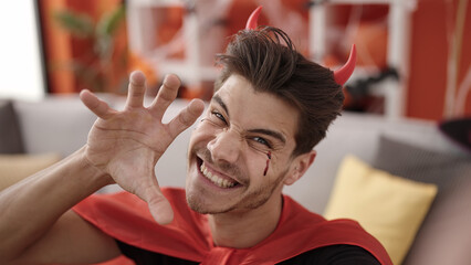 Wall Mural - Young hispanic man wearing devil costume doing scare gesture at home