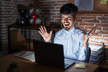 young hispanic man with beard working at the office at night celebrating mad and crazy for success w