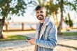 © Krakenimages.com - Young hispanic man smiling confident using smartphone at park