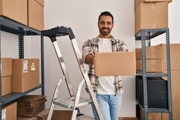 Canvas Print - Young hispanic man ecommerce business worker holding package standing at office