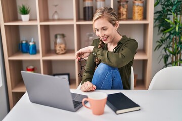 Wall Mural - Young blonde woman using laptop drinking coffee at home