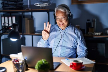 Canvas Print - Hispanic senior man wearing call center agent headset at night showing and pointing up with fingers number three while smiling confident and happy.