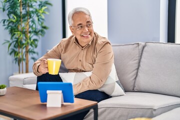 Wall Mural - Senior man drinking coffee watching touchpad at home