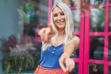 Wall Mural - Young blonde woman smiling confident pointing with fingers at street