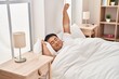 © Krakenimages.com - Young chinese man stretching arms lying on bed at bedroom