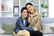 © Liubomir - Portrait of family, mother and teenage son sitting on sofa at home and hugging, smiling at camera.