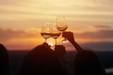 Fototapeta Natura - A group of girlfriends raise a toast with glasses of white wine on a sunset. Close shot.	
