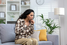 Woman Having Cold And Sick Coughing Sitting On Couch At Home, Hispanic Woman In Living Room With Cold And Flu.