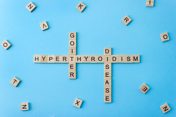 Words Hyperthyroidism Goiter and Disease on wooden blocks with letters on blue background. Thyroid treatment concept. Selective focus