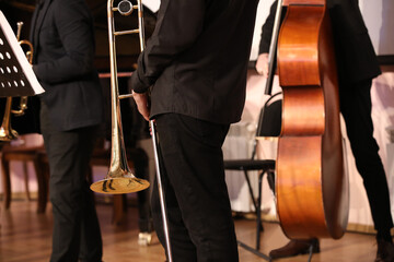 Wall Mural - A group of jazz musicians playing a concert while standing on the stage with a golden trombone in hand close-up