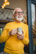 © Miljan Živković - One senior man stand in at door of tiny house happy smile hold cup