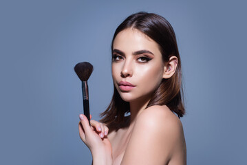 Young woman applies powder on the face using makeup brush. Beautiful girl doing contouring apply blush on cheeks. Face beauty cosmetics. Fresh skin and natural make up. Powder blush on facial skin.