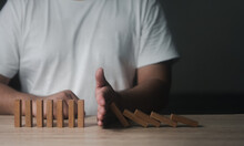 Closeup Image Of A Man Try To Stop Falling Wooden Dominoes Blocks For Business Solution Concept. Risk Insurance Concept, Crisis Manager, Domino Principle