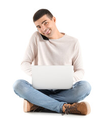 Poster - Handsome guy with laptop talking by mobile phone on white background