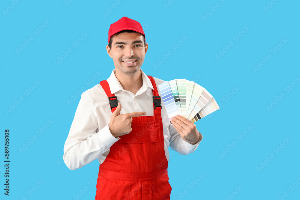 Male painter pointing at color palettes on blue background