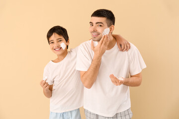 Poster - Father and his little son applying shaving foam onto faces against beige background