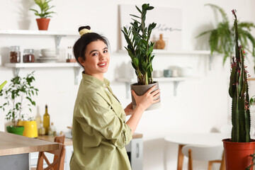 Canvas Print - Young woman with green houseplant in kitchen