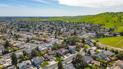 Wall Mural - Drone photos over the city of Antioch, California on a beautiful blue day with green hills, homes and streets.