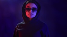 Portrait fashion subculture futuristic woman in eyeglasses black hoodie vogue posing neon backlit