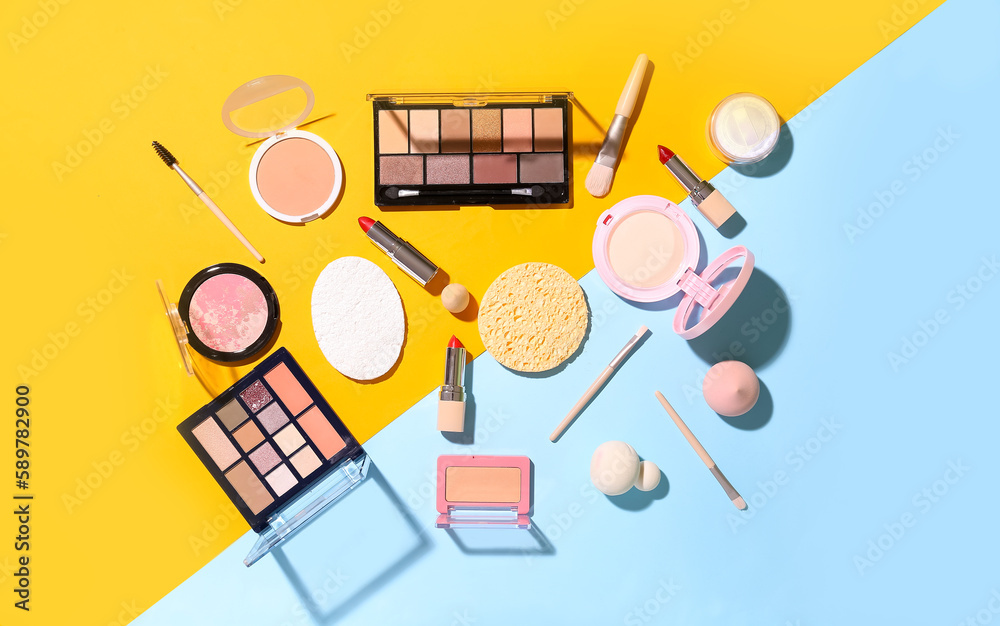 Decorative cosmetics with makeup brushes and sponges on color background
