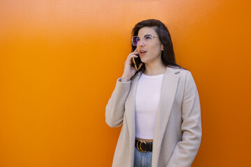 Wall Mural - Copyspace photo of a charming stylish model, talking on her mobile phone, wearing office clothes, isolated on vivid color background